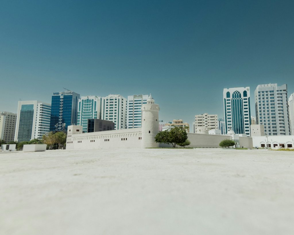 a large white building with a lot of tall buildings in the background Qasr Al Hosn