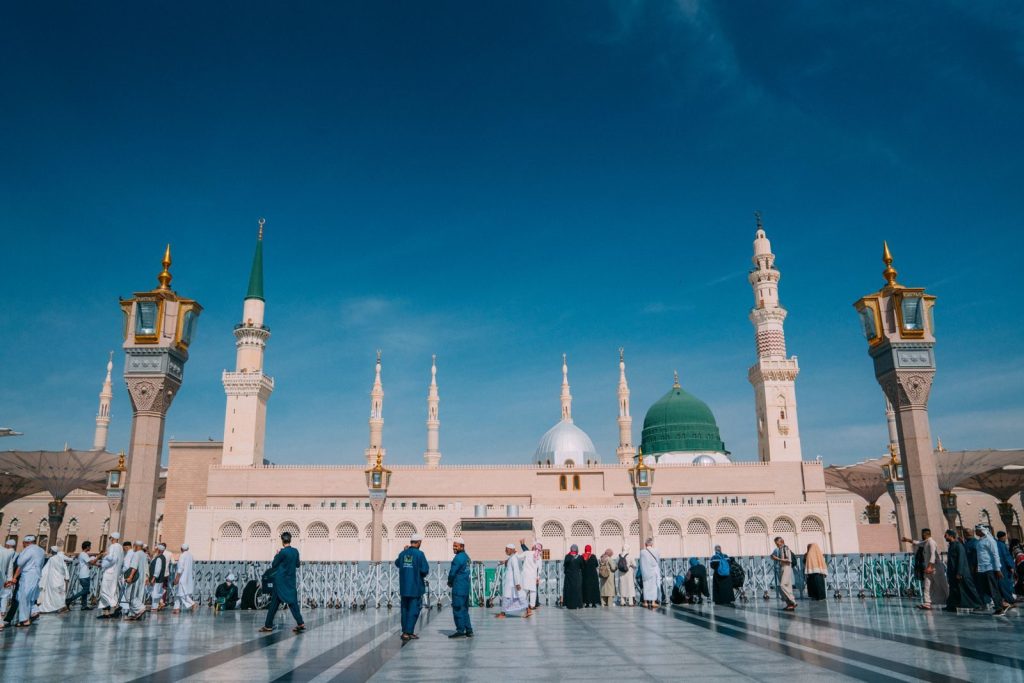 Captivating image of the Prophet's Mosque with visitors under a clear blue sky in Medina.